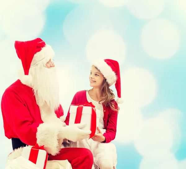 Niña sonriente con santa claus y regalos — Foto de Stock