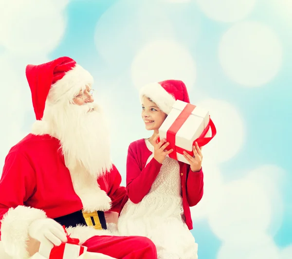 Smiling little girl with santa claus and gifts — Stock Photo, Image
