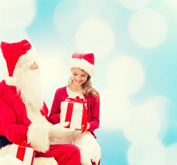 Petite fille souriante avec santa claus et cadeaux Photo De Stock