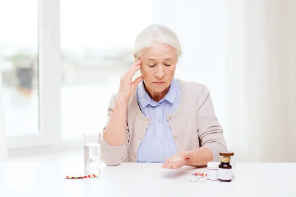 Senior woman with water and medicine at home — Stock Photo, Image