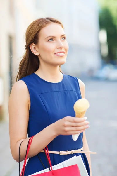 Женщина с пакетами для покупок и мороженым — стоковое фото