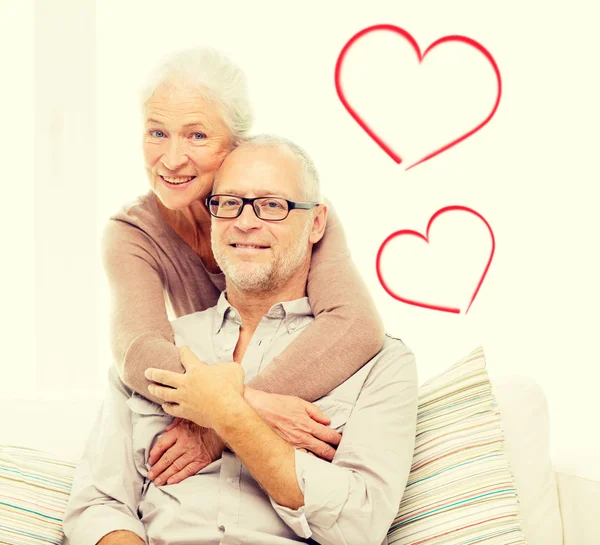 Счастливая пожилая пара обнимается на диване дома — стоковое фото