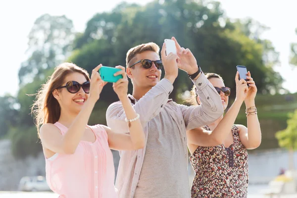 Amigos sonrientes con teléfono inteligente tomando fotos — Foto de Stock