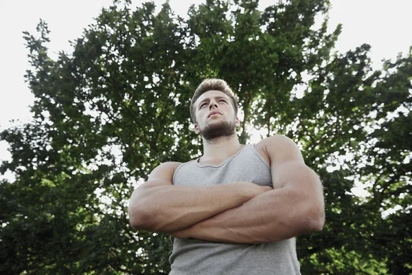 Sportlicher junger Mann mit verschränkten Armen im Sommerpark — Stockfoto