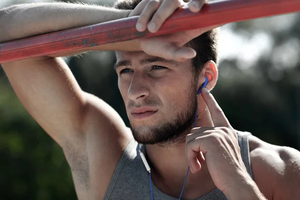 Young man with earphones and horizontal bar — Stock Photo, Image