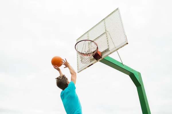 Mladý muž hraje basketbal venku — Stock fotografie