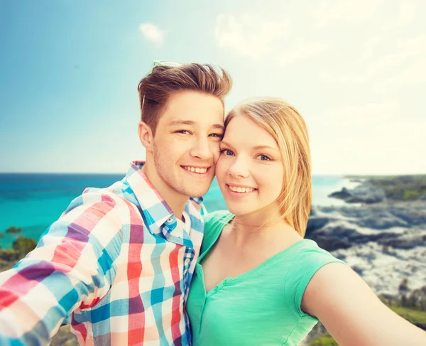 Smiling couple with smartphone on summer beach — Stock Photo, Image
