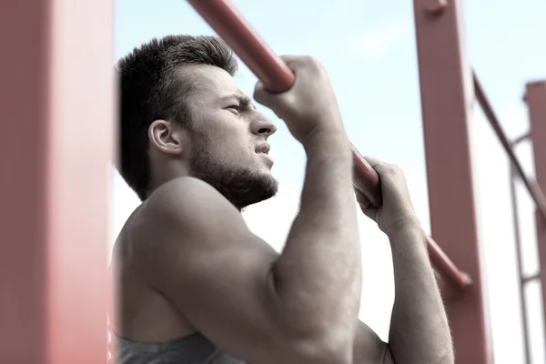 Young man exercising on horizontal bar outdoors — Stock Image Young man exercising on horizontal bar outdoors Royalty Free Stock Images