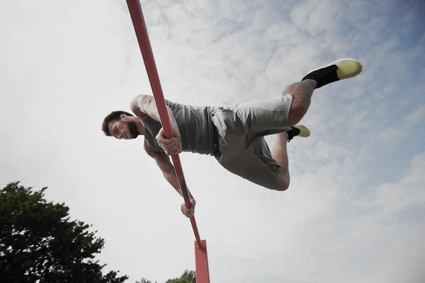 Jonge man uit te oefenen op horizontale balk — Stockfoto