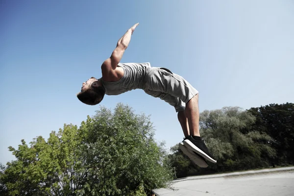 Sportieve jonge man springen in zomer park — Stockfoto