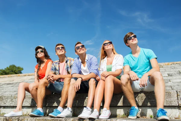 Gruppo di amici sorridenti seduti sulla strada della città — Foto Stock