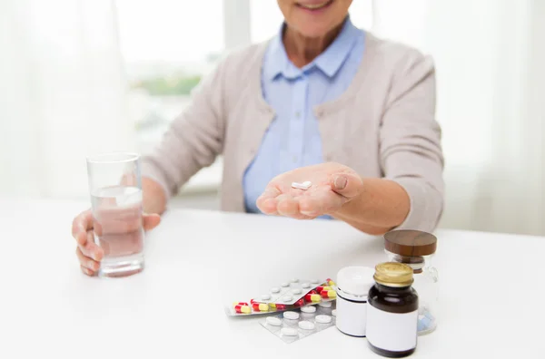 Happy senior woman with water and pills at home — Stock Photo, Image