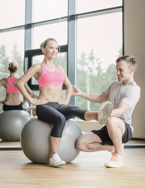 Sonriente hombre y mujer con bola de ejercicio en el gimnasio —  Fotos de Stock