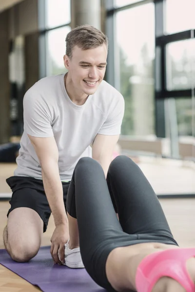 Donna sorridente con allenatore di sesso maschile che esercita in palestra — Foto Stock