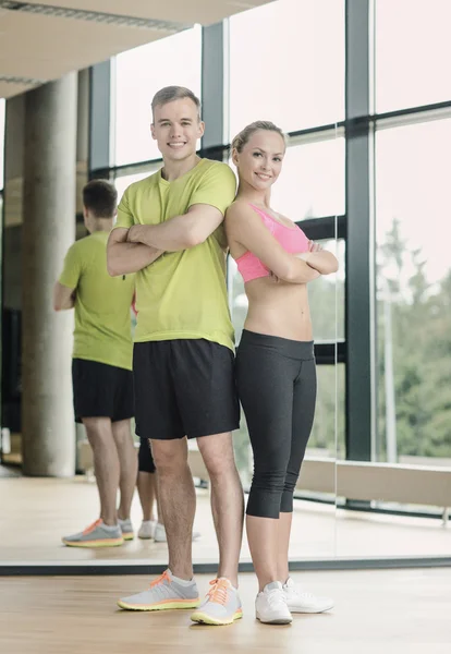 Sonriente hombre y mujer en el gimnasio — Foto de Stock