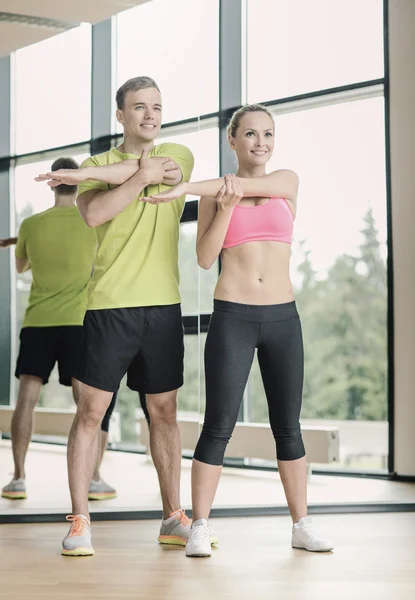 微笑的男人和女人在健身房锻炼身体 — 图库照片