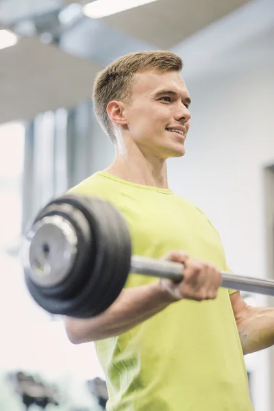 Hombre sonriente haciendo ejercicio con barra en el gimnasio — Foto de Stock