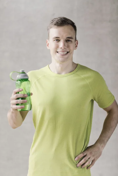 Smiling man with bottle of water in gym — Stock Photo, Image