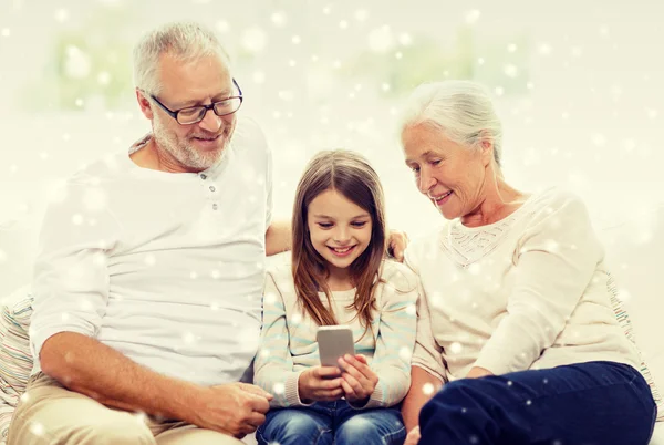 Χαμογελώντας οικογένεια με smartphone στο σπίτι — Φωτογραφία Αρχείου