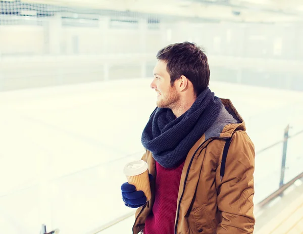 Glücklicher junger Mann mit Kaffeetasse auf Eisbahn — Stockfoto