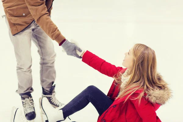 Hombre ayudando a las mujeres a levantarse en pista de patinaje — Foto de Stock