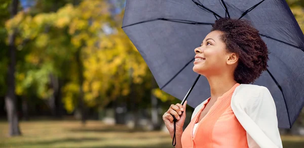 Happy african woman with umbrella in autumn park — Stock Photo, Image