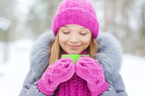 Sonriente joven con taza en el bosque de invierno — Foto de Stock