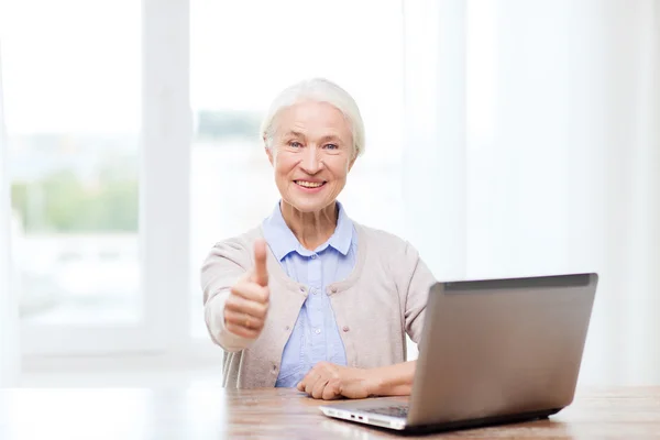 Щаслива старша жінка з ноутбуком, що показує великі пальці вгору — стокове фото