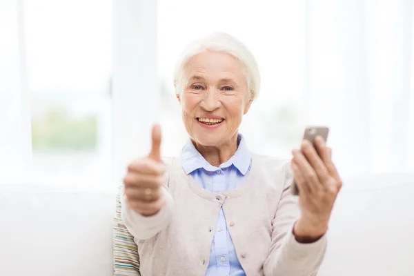 Пожилая женщина со смартфоном показывает большие пальцы вверх — стоковое фото