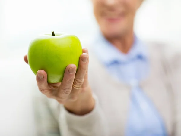 Närbild på senior kvinna hand innehav grönt äpple — Stockfoto