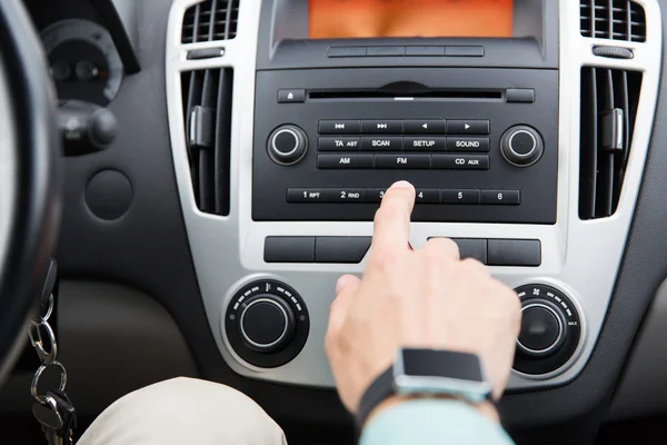 Gros plan de la main masculine tournant sur la radio dans la voiture — Photo