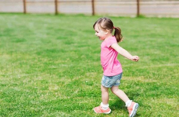Menina feliz correndo no campo de verão verde — Fotografia de Stock