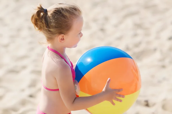 Heureuse petite fille jouant ballon gonflable sur la plage — Photo