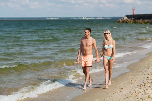 Gelukkige paar in badmode wandelen op het strand — Stockfoto