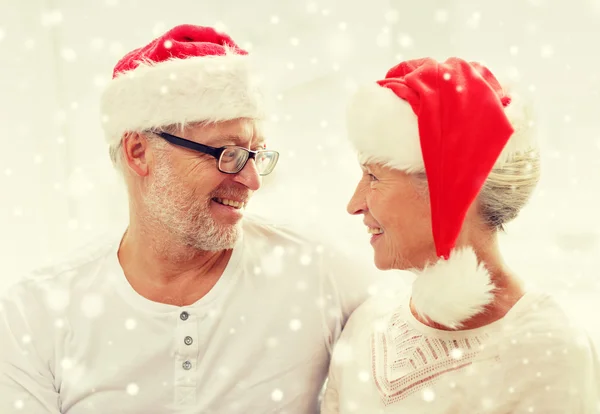 Feliz pareja de ancianos en santa helper sombreros en casa —  Fotos de Stock