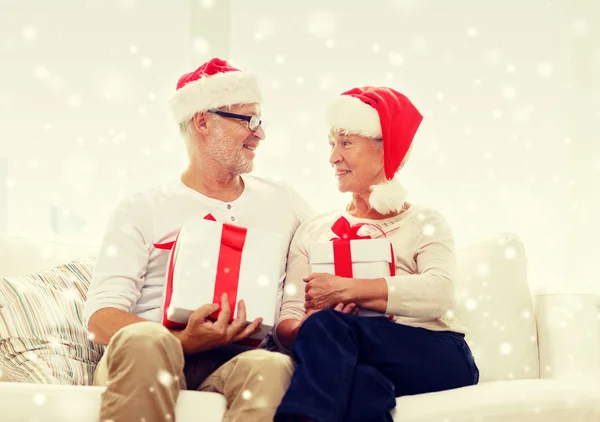 Felice coppia di anziani in cappelli di Babbo Natale con scatole regalo — Foto Stock