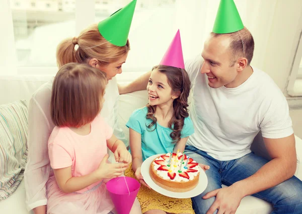 Smiling family with two kids in hats with cake — Stock Photo, Image