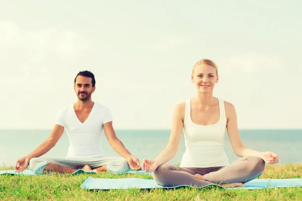 Coppia fare esercizi di yoga all'aperto — Foto Stock