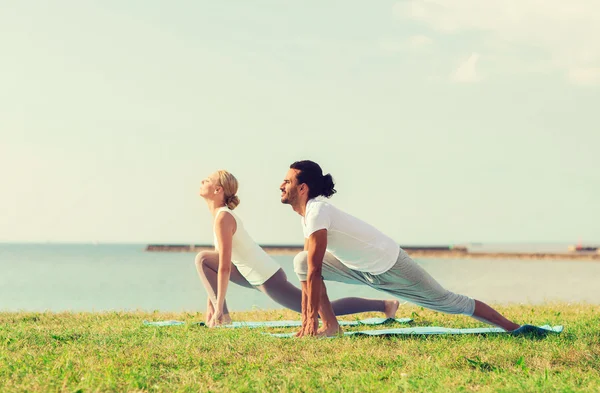 Casal fazendo exercícios de ioga ao ar livre — Fotografia de Stock