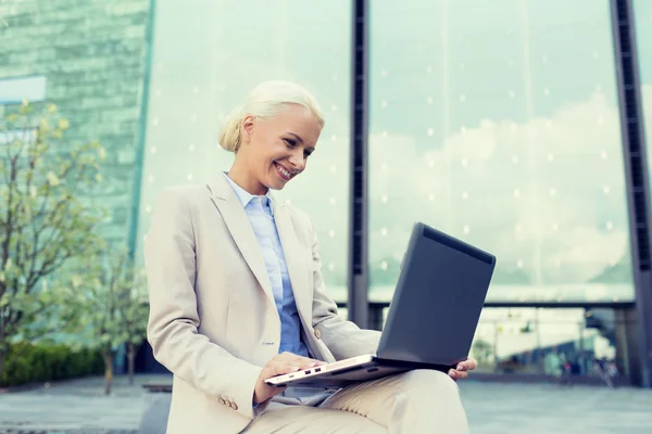 Smiling businesswoman working with laptop outdoors — Stock Photo, Image