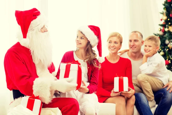 Lachende familie met santa claus en geschenken thuis — Stockfoto