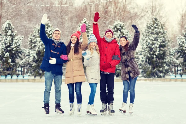 Amigos felices patinaje sobre hielo en pista al aire libre — Foto de Stock