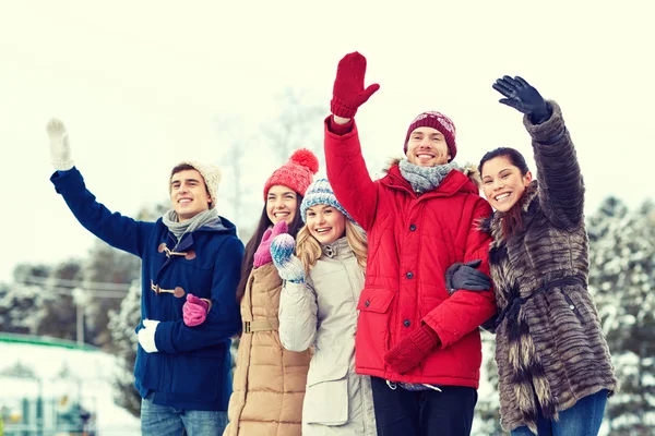 Happy friends waving hands on ice rink outdoors — Stock Photo, Image