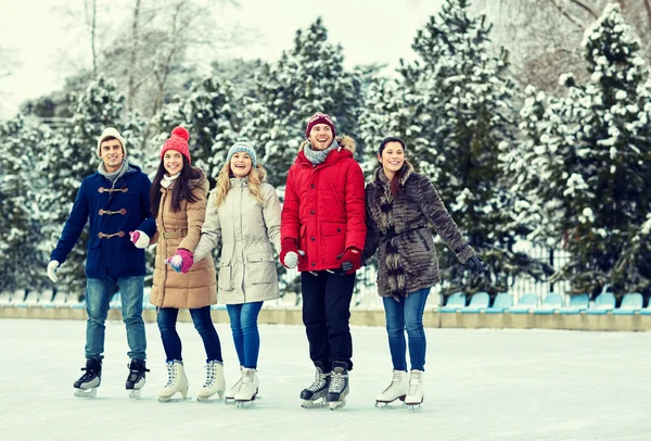 Amigos felizes patinação no gelo no ringue ao ar livre — Fotografia de Stock