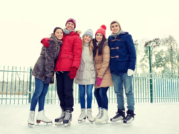 Amigos felices patinaje sobre hielo en pista al aire libre —  Fotos de Stock