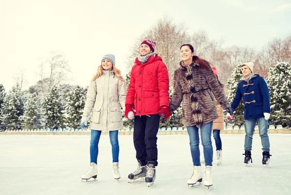 Happy friends ice skating on rink outdoors — Stock Photo, Image