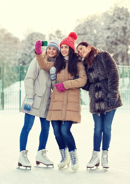 Happy young women with smartphone on skating rink — Stock Photo, Image