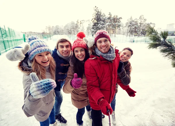 Happy friends with smartphone on ice skating rink — Stock Photo, Image