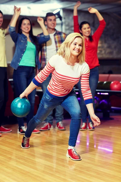 Glückliche junge Frau wirft Ball in Kegelclub — Stockfoto