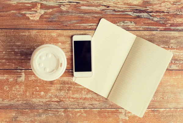 Close up of notebook, coffee cup and smartphone — Stock Photo, Image